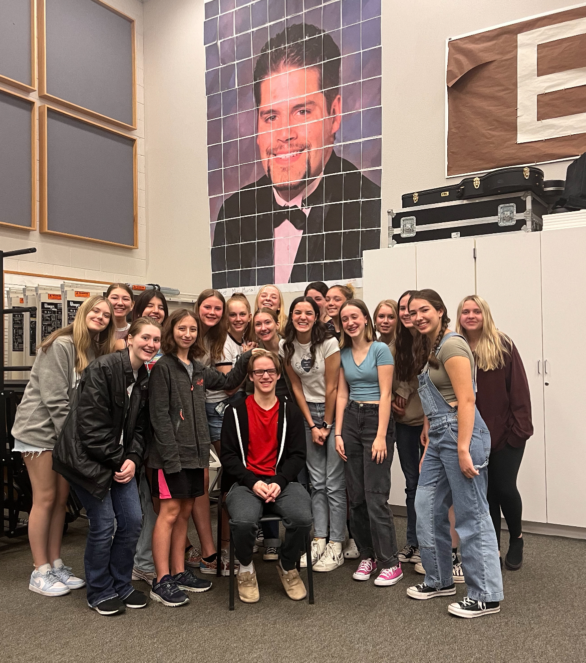 The Eagle High Choir students celebrate the end of their rehearsals and are excited to start their winter performance. They stand in front of a mural of choir teacher Seth Mcmullen. 