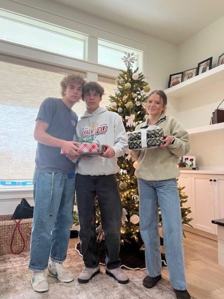 Senior Dustin Todd, senior Thomas Stevens and junior Elizabeth Baruch hold presents next to a Christmas tree. Many students at Eagle High will share the Christmas spirit by giving gifts to their friends and family members this year. 
