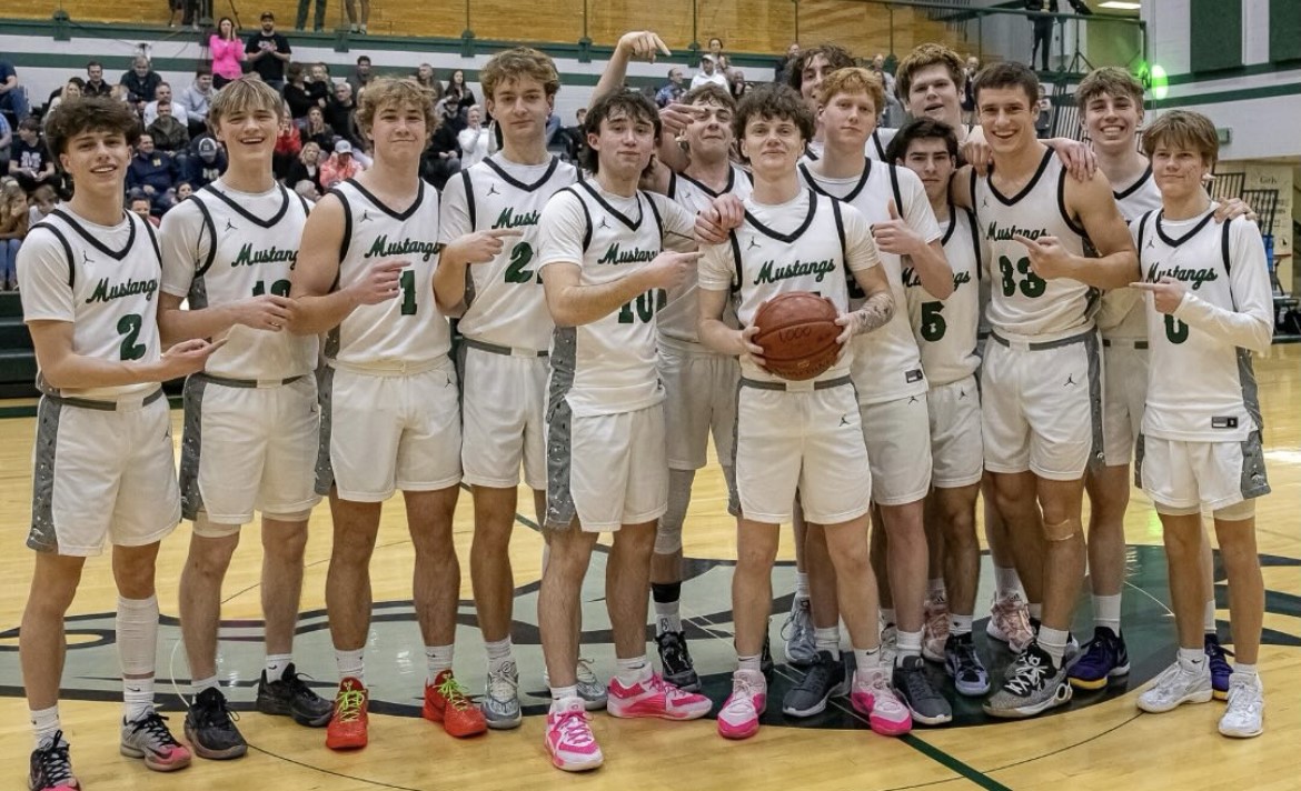 The Eagle High varsity basketball team stands on the court after a game. The team takes a picture to commemorate senior Russel Gibson’s 1000 high school career points scored.  