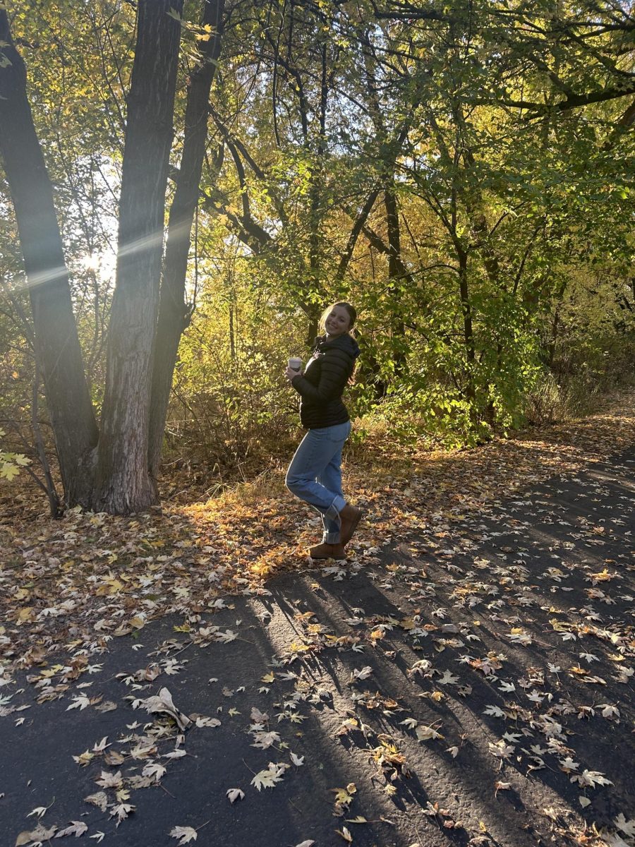 Sophomore Katrina Collins poses in her fall fashion outfit, standing on the Greenbelt trail. She loves the fall leaves because they inspire her fall outfits.