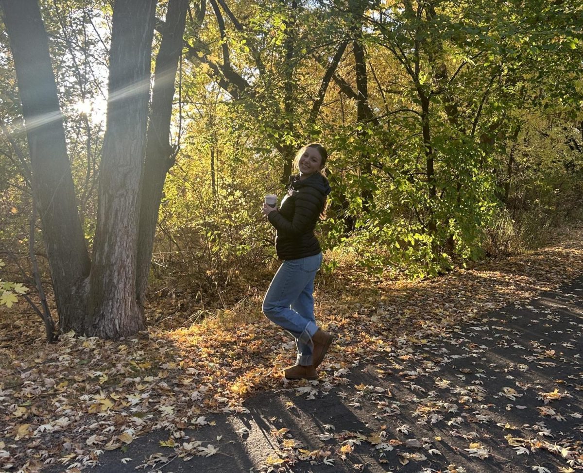 Sophomore Katrina Collins poses in her fall fashion outfit, standing on the Greenbelt trail. She loves the fall leaves because they inspire her fall outfits.