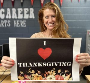 College Counselor Bria Bodine shows her love of Thanksgiving by holding a sign in her office. She created this special sign herself. Her memories inspired her passion for this holiday.