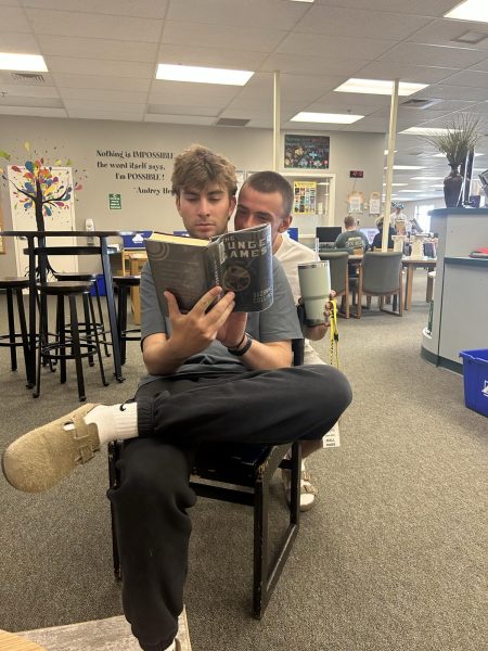 Seniors Beau Saur and Brady Ford read a “Hunger Games” book in the Eagle High library. The Eagle High library has a large selection of dystopian books, such as “The Hunger Games.”