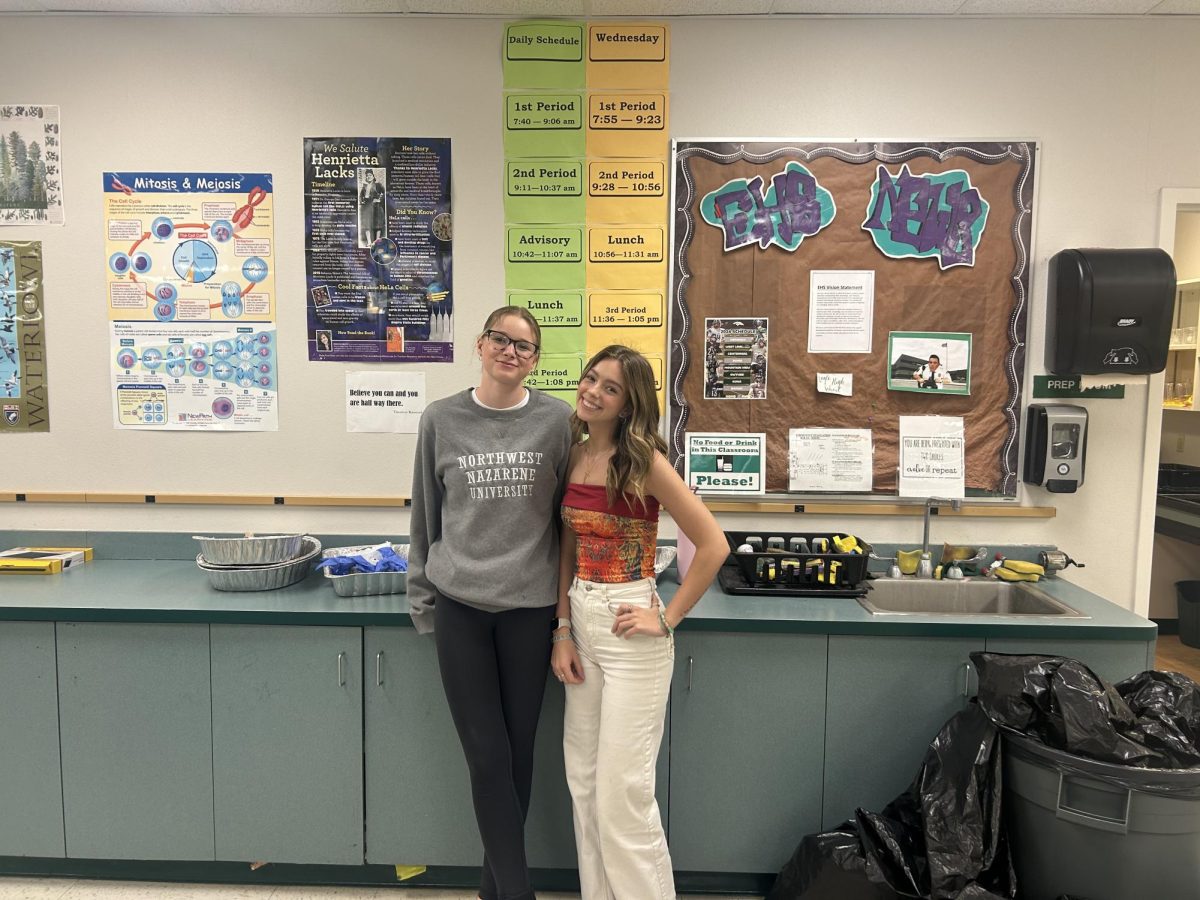 Seniors Savannah Bub and Rylie Shoemaker stand in front of the current school schedule. Many Eagle High teachers have similar schedules posted in their classrooms. 