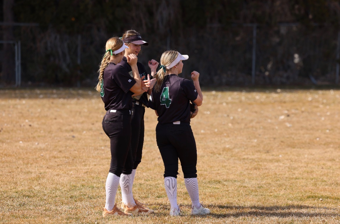 Senior Alyson Viera, junior London Sanfilipo-Cook and sophomore Reese Norcutt gather on the outfield to assess a play in a game against Ridgevue High. Outfield players that have a strong plan of action are critical to a successful game.
