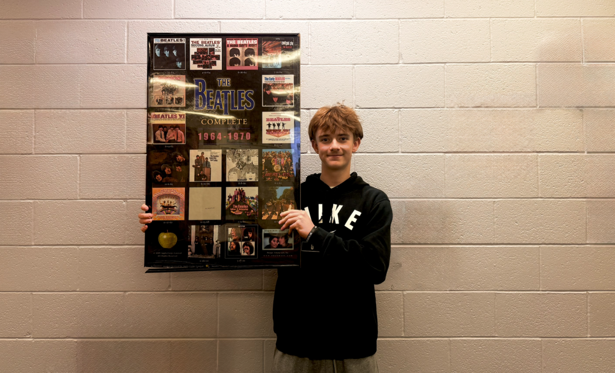 Sophomore Brandon Zins holds a Beatles poster. The Beatles are a very popular old band that students with older music taste love to listen to.